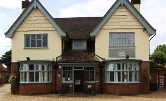 a two - story building with a brown roof and white trim , featuring large windows and a sign on the side at The Queen Victoria