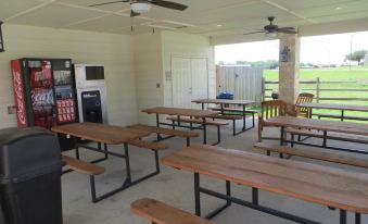 an outdoor dining area with multiple tables and benches , as well as a soda machine at Hotel Texas Cuero