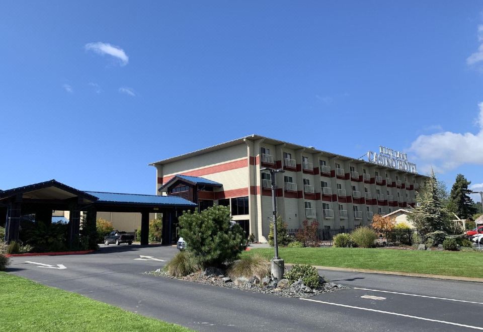 a large hotel building with a red and white facade , surrounded by grass and trees at Blue Lake Casino and Hotel