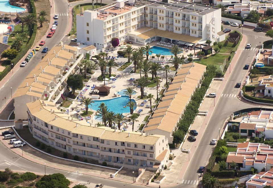 a bird 's eye view of a resort with a pool surrounded by buildings and palm trees at Globales Los Delfines