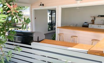 a modern kitchen with white walls and wooden cabinets , featuring a counter with stools , an air conditioner , and plants at Little Palm Cabins