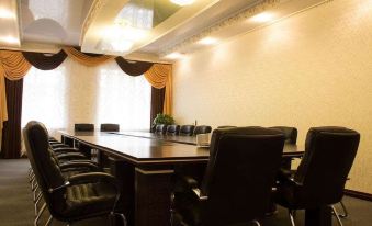 a conference room with a long wooden table surrounded by black chairs and a yellow curtain at Metropol Hotel