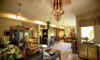 a spacious , well - lit hotel lobby with various seating options , a reception desk , and a chandelier at Baan Amphawa Resort & Spa