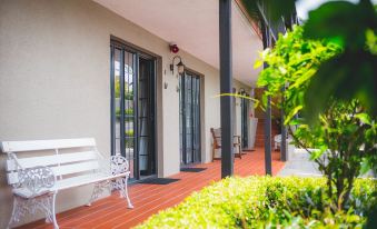 a white bench on a wooden deck with an open door leading to a house at Knights Inn