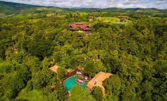a large house with a swimming pool is surrounded by lush greenery and overlooks a golf course at Phu Pha Nam Resort
