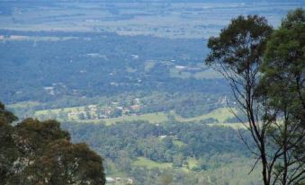 a view from a hilltop , with trees and buildings visible in the distance , overlooking a forested area at Archibald Hotel