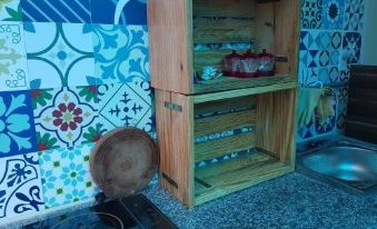a wooden cabinet with a drawer and shelves , placed in a room with colorful tiles on the walls at Sen Villa Boutique