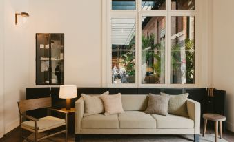 a modern living room with a white couch and two chairs , positioned near a window that overlooks a courtyard at August