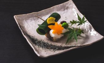 a square white plate with a variety of food items and greenery on it , including green beans , carrots , and yellow flowers at Kamisuwa Onsen Shinyu