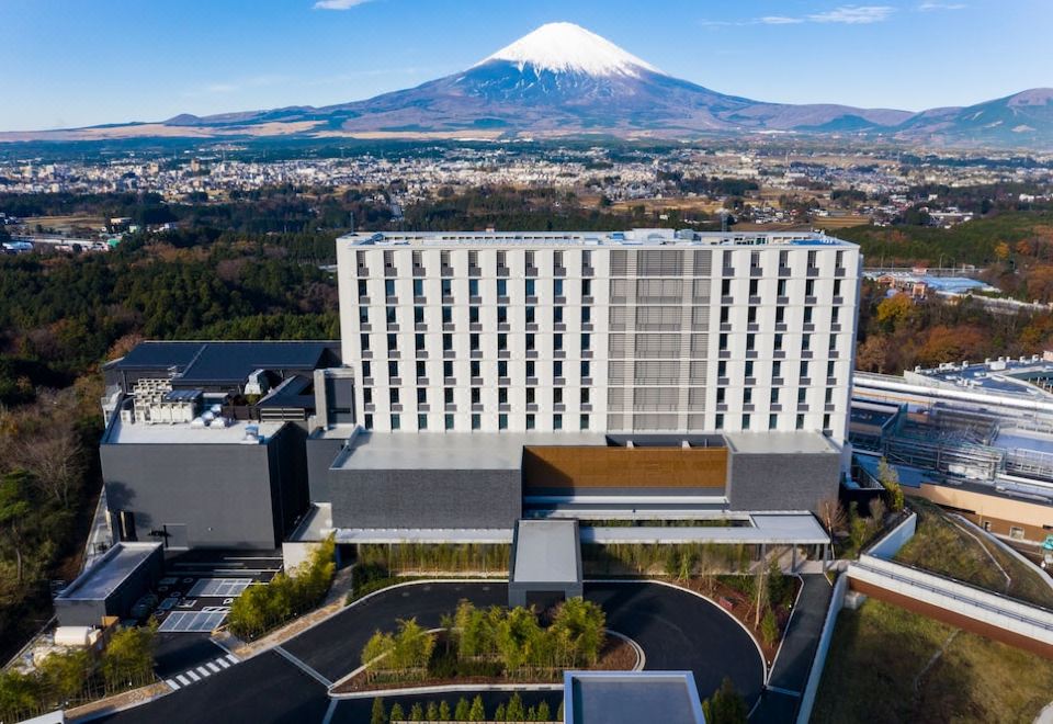 a large hotel building with a snow - covered mountain in the background , surrounded by trees and mountains at Hotel Clad