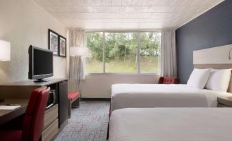 a modern hotel room with a large window , white bed , and red accent chair , along with other amenities such as a tv and desk at Ramada by Wyndham Uniontown