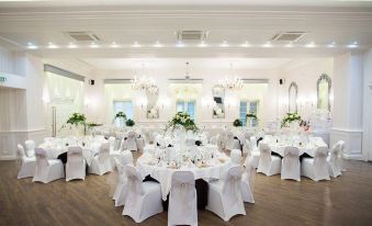 a large dining room with multiple round tables covered in white tablecloths and adorned with floral centerpieces at Cbh Hythe Imperial Hotel Golf and Spa