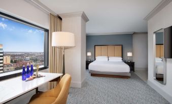 a modern hotel room with a large bed , desk , and chair , as well as a view of the city through a large window at Hyatt Regency Dulles