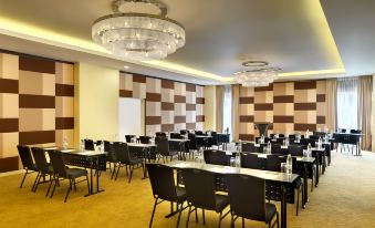 a large conference room with rows of tables and chairs , a chandelier , and brown walls at Best Western I-City Shah Alam