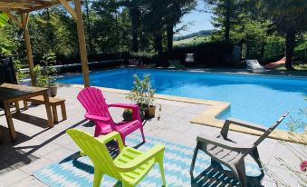 a backyard with a pool surrounded by patio furniture , including chairs and a dining table at Le Bellevue