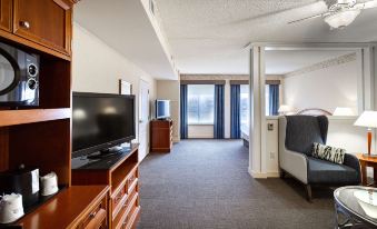a hotel room with a large flat - screen tv mounted on the wall , a couch , and a dining table at Hilton Garden Inn Wooster