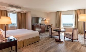 a spacious hotel room with a large bed , a desk , and a window overlooking the city at DiplomaticHotel