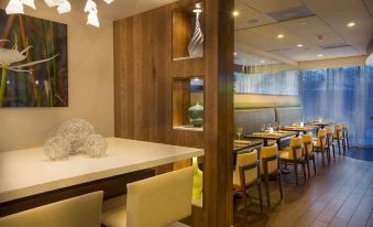 a modern restaurant with a wooden dining table and chairs , as well as a bar area at Aloft Miami Dadeland