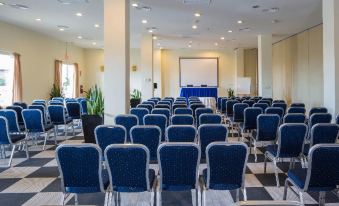 a large conference room with rows of blue chairs arranged in a semicircle , and a projector screen at the front at Grand Palladium Lady Hamilton Resort & Spa - All Inclusive