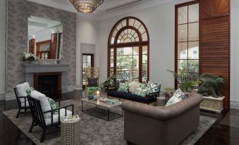 a modern living room with a brown couch , coffee table , and chandelier , as well as large windows and arched doorways at Rydges Southbank Townsville, an EVT hotel