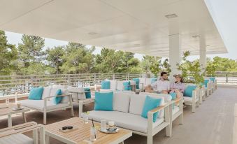 a group of people sitting outside on a patio , enjoying each other 's company and the view at Bluesun Hotel Elaphusa