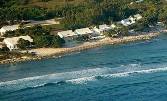 a bird 's eye view of a beach with houses and trees surrounding it , and waves crashing in the foreground at Paradise Villas