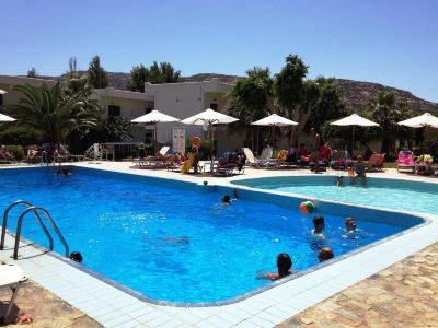 a group of people are swimming in a large outdoor pool with umbrellas and lounge chairs at Valley Village