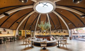 a modern restaurant with a curved ceiling and wooden beams , featuring a dining area with chairs and tables at Barceló Tenerife