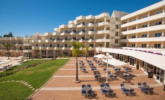 a large hotel with multiple buildings , some of which have umbrellas and have tables and chairs set up on the lawn at Vila Gale Nautico