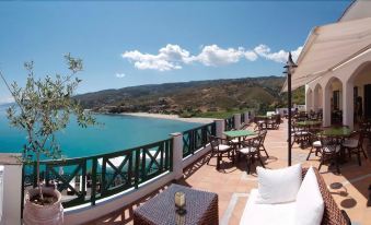 a balcony overlooking a body of water , with several chairs and tables placed on the deck at Erofili Beach Hotel