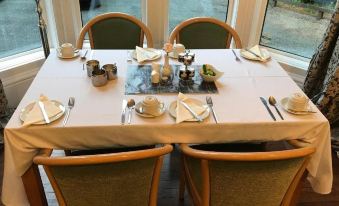 a dining table set for breakfast , with multiple plates , cups , and utensils arranged neatly on the table at Balcary House Hotel