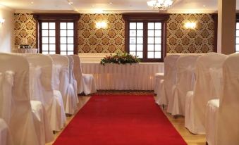 a long red carpet leads to a set of white chairs in a room with a large window at Mulroy Woods Hotel
