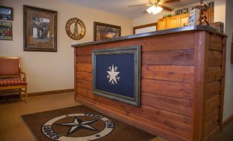 a wooden reception desk with a framed blue sign and framed star logo in the background at Texas Star Lodges