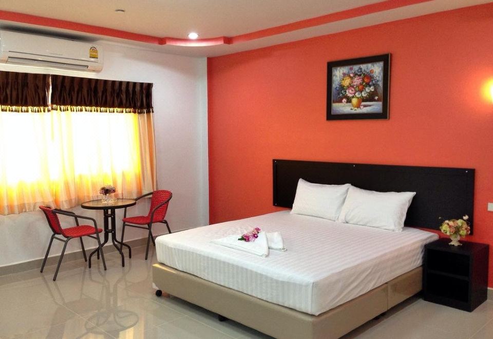 a clean and well - organized hotel room with a double bed , a dining table , and a chair at P.K Inn