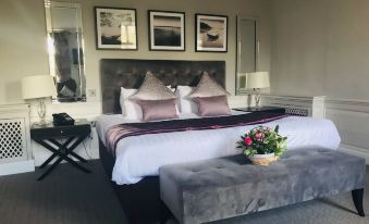 a luxurious bedroom with a king - sized bed , a grey couch , and a painting on the wall at Cartwright Hotel