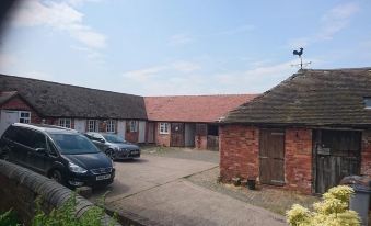 a courtyard with two buildings , one on the left side and the other on the right side , surrounded by a brick wall at Church Farm Accommodation