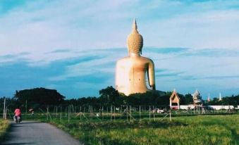 a large golden buddha statue in a grassy field , with a blue sky in the background at Smile Resort