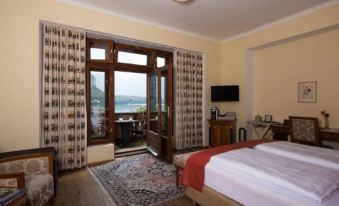a hotel room with a king - sized bed , a tv , and a window overlooking a beautiful view at Seehotel Grüner Baum