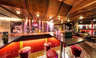 a modern bar with wooden ceiling , red and purple walls , and various bottles and glasses on the shelves at Berghotel Bastei