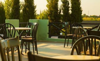 an outdoor dining area with tables and chairs , surrounded by green trees and a body of water at Holiday Village