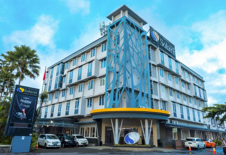 a modern hotel building with a blue and yellow exterior , located in a city setting at Solaris Hotel Malang