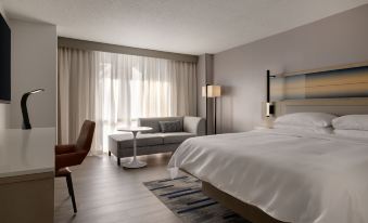 a modern hotel room with a large bed , couch , and desk , all neatly arranged in a minimalist style at Marriott Saddle Brook