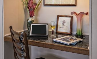 a wooden desk with a laptop , wine glass , and a vase of flowers next to a vase at The Old Wailuku Inn at Ulupono