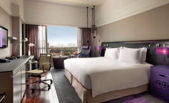 The bedroom is furnished with large windows, a bed, and a desk in the middle at Sofitel Saigon Plaza