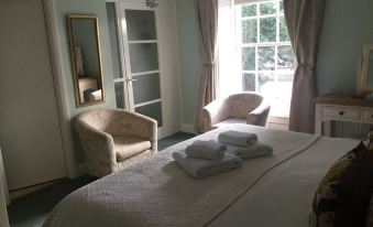 a bedroom with a large bed , two chairs , and a window overlooking a beautiful view at The Coachman Inn