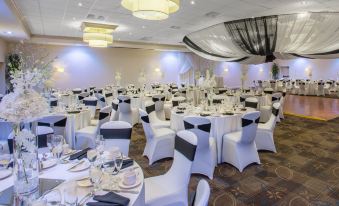 a large banquet hall with multiple tables covered in white tablecloths and chairs arranged for a formal event at Crowne Plaza Boston - Woburn, an IHG Hotel