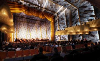 a large auditorium filled with people sitting in chairs , watching an orchestra perform on stage at SpringHill Suites Florence