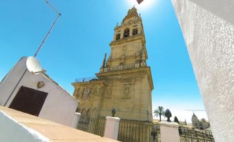 a tall bell tower with a stone base and white walls , standing in the middle of a sunny day at La Torre