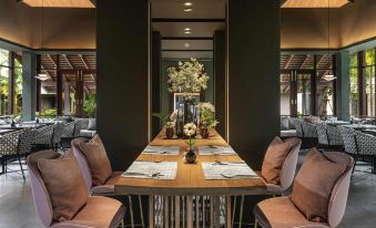 a long dining table surrounded by chairs in a room with black walls and gold accents at Grand Mercure Khao Lak Bangsak