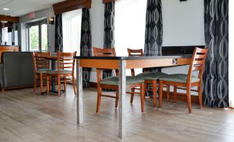 a dining room with wooden tables and chairs , along with black curtains on the windows at SureStay Hotel by Best Western Bowling Green North